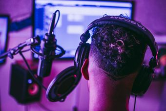 A man is wearing headphones and a microphone in a recording studio.