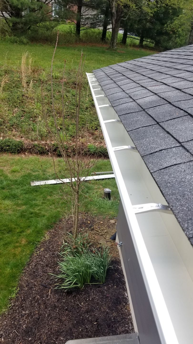 A white house with a black gutter and a blue sky.