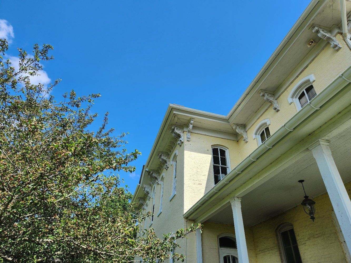 A house with a gutter on the side of it and trees.