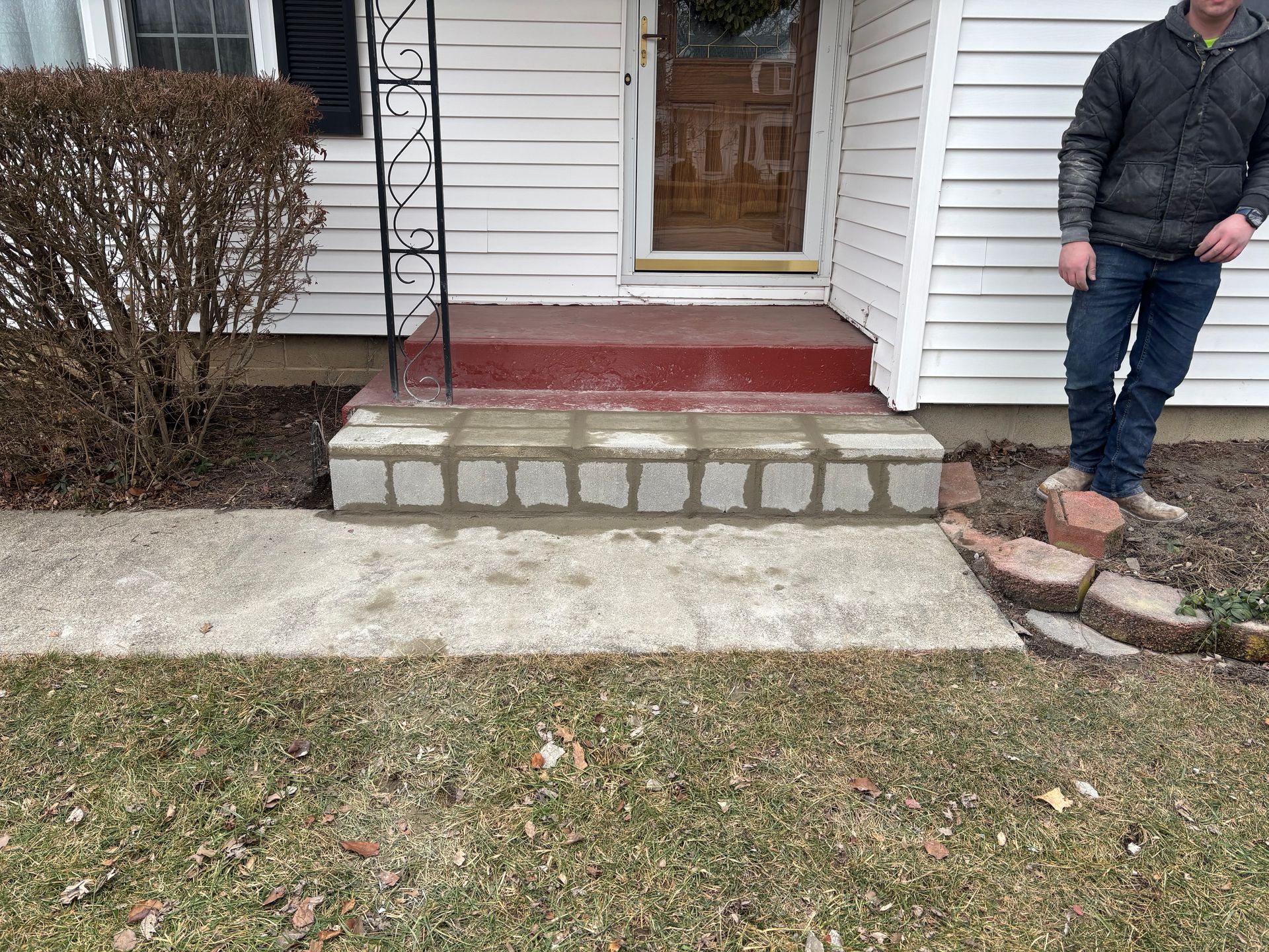 A person standing near a newly constructed brick and concrete front step.