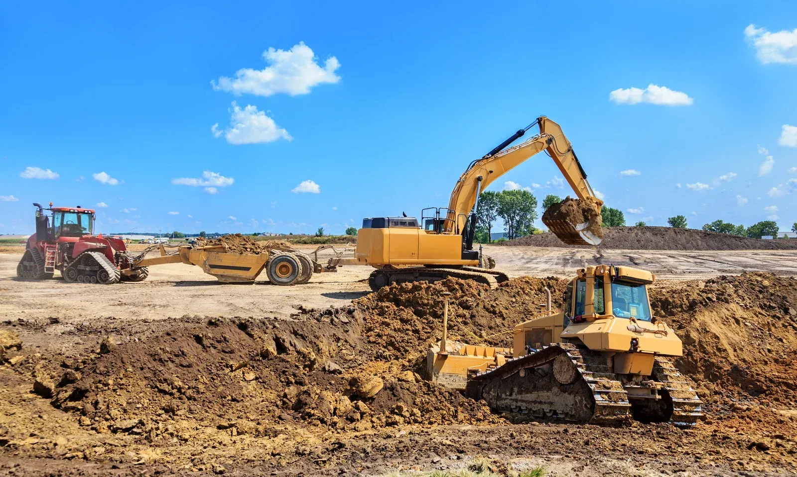 Construction site: Yellow excavators and bulldozer digging earth under a blue sky.