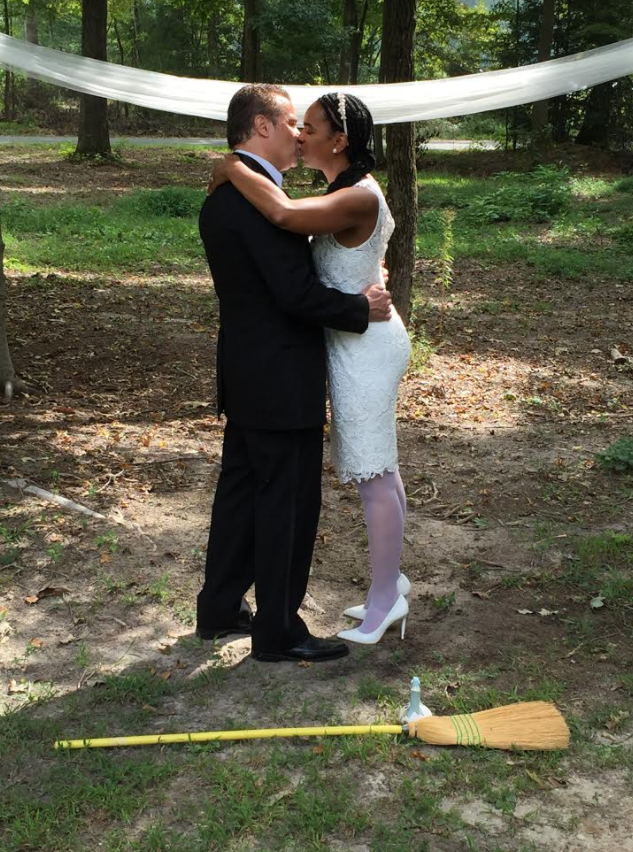 Couple in formal attire kissing outdoors at a wedding ceremony