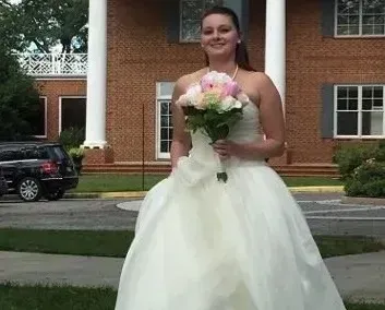 Woman in a white gown holding a bouquet outside a brick building