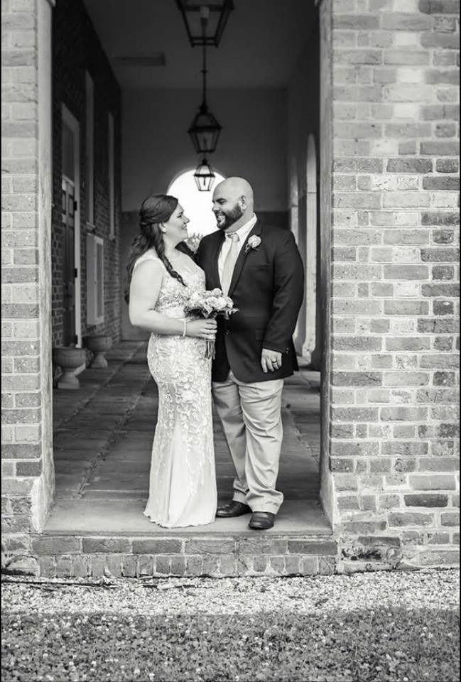 Wedding couple standing in a brick doorway, holding hands and smiling at each other