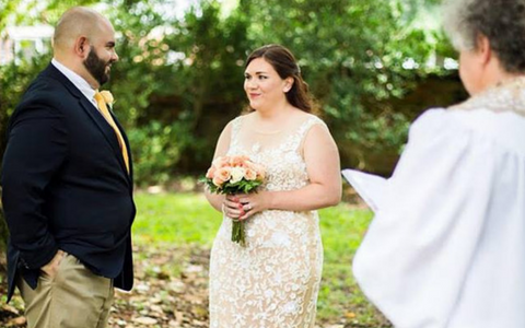 Bride holding bouquet during outdoor wedding ceremony, facing officiant and man in suit