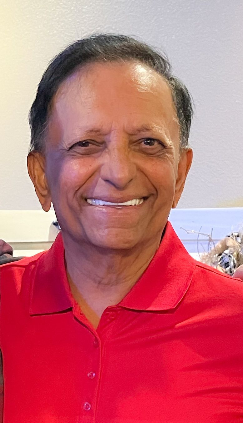 A man in a red shirt is smiling for the camera.