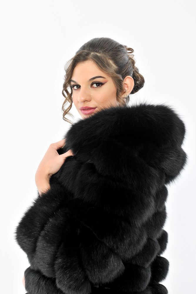 Due donne in posa in un ambiente bianco, con indosso giacche di pelliccia bianche e nere.