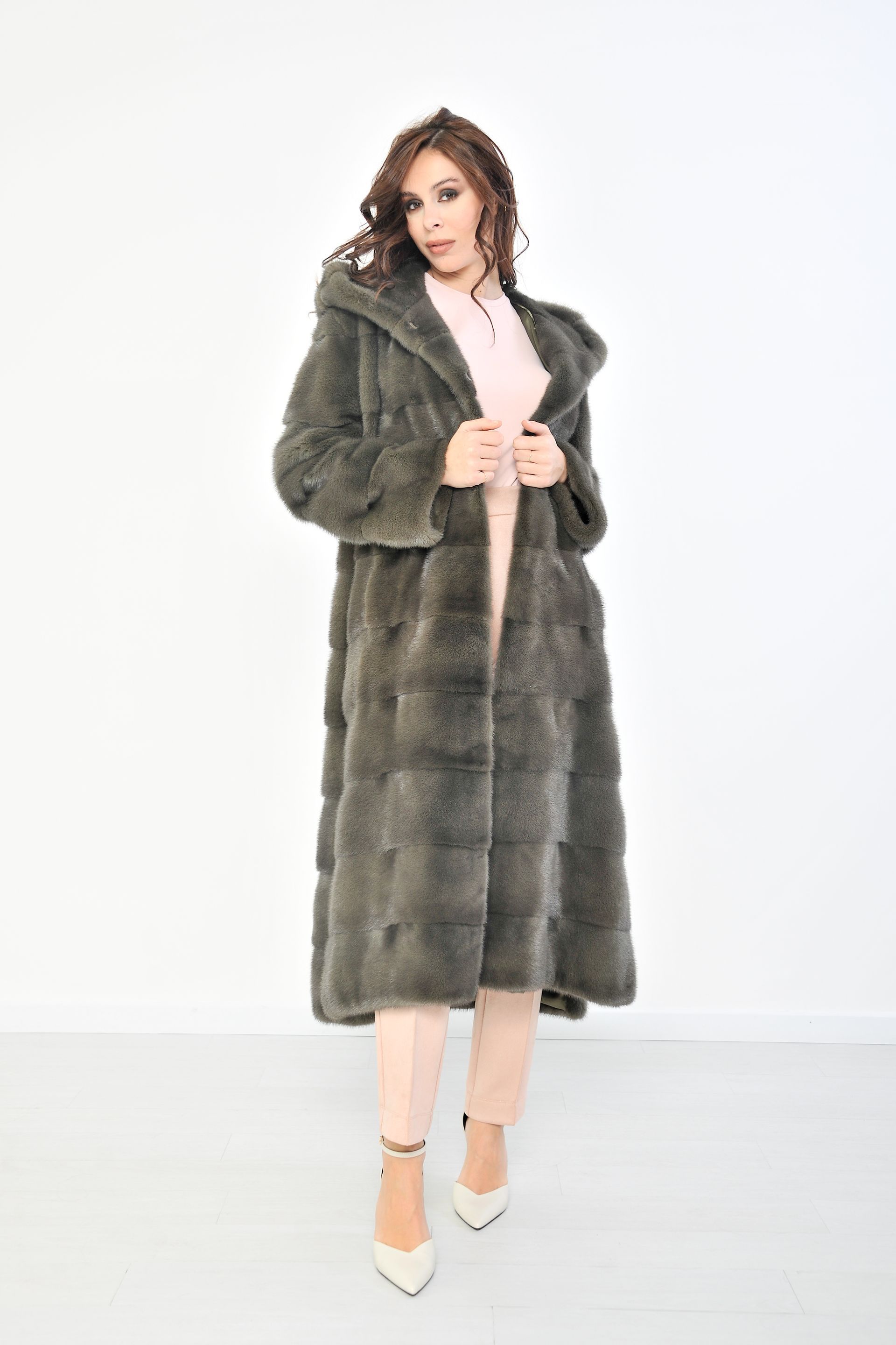 Donna con pelliccia e cappuccio, in piedi su uno sfondo bianco.