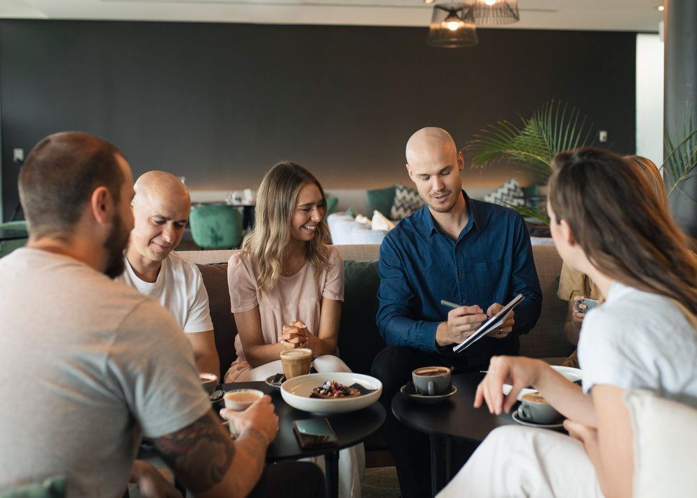 A Group Of People Are Seated Around A Table In A Restaurant — St. John Imagery In Sydney, NSW