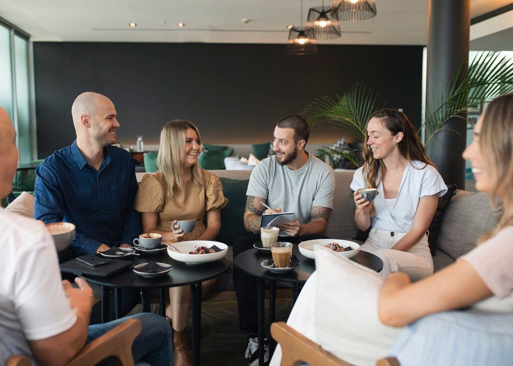 A Group Of People Are Sitting Around A Table In A Restaurant — St. John Imagery In Sydney, NSW