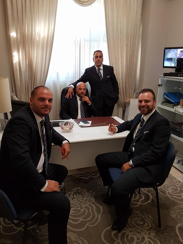 quattro uomini in giacca nera in un ufficio