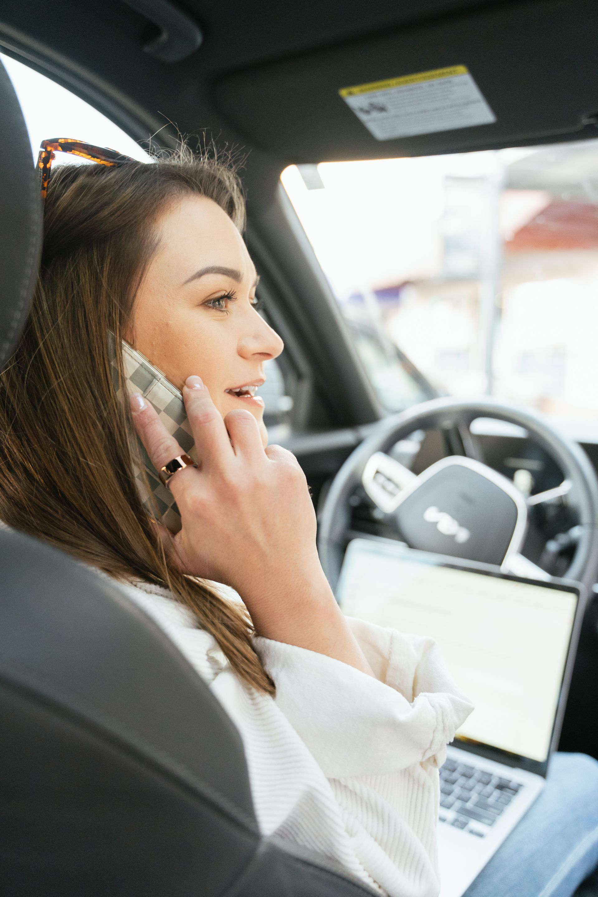 Bree is sitting in a car talking on a cell phone.