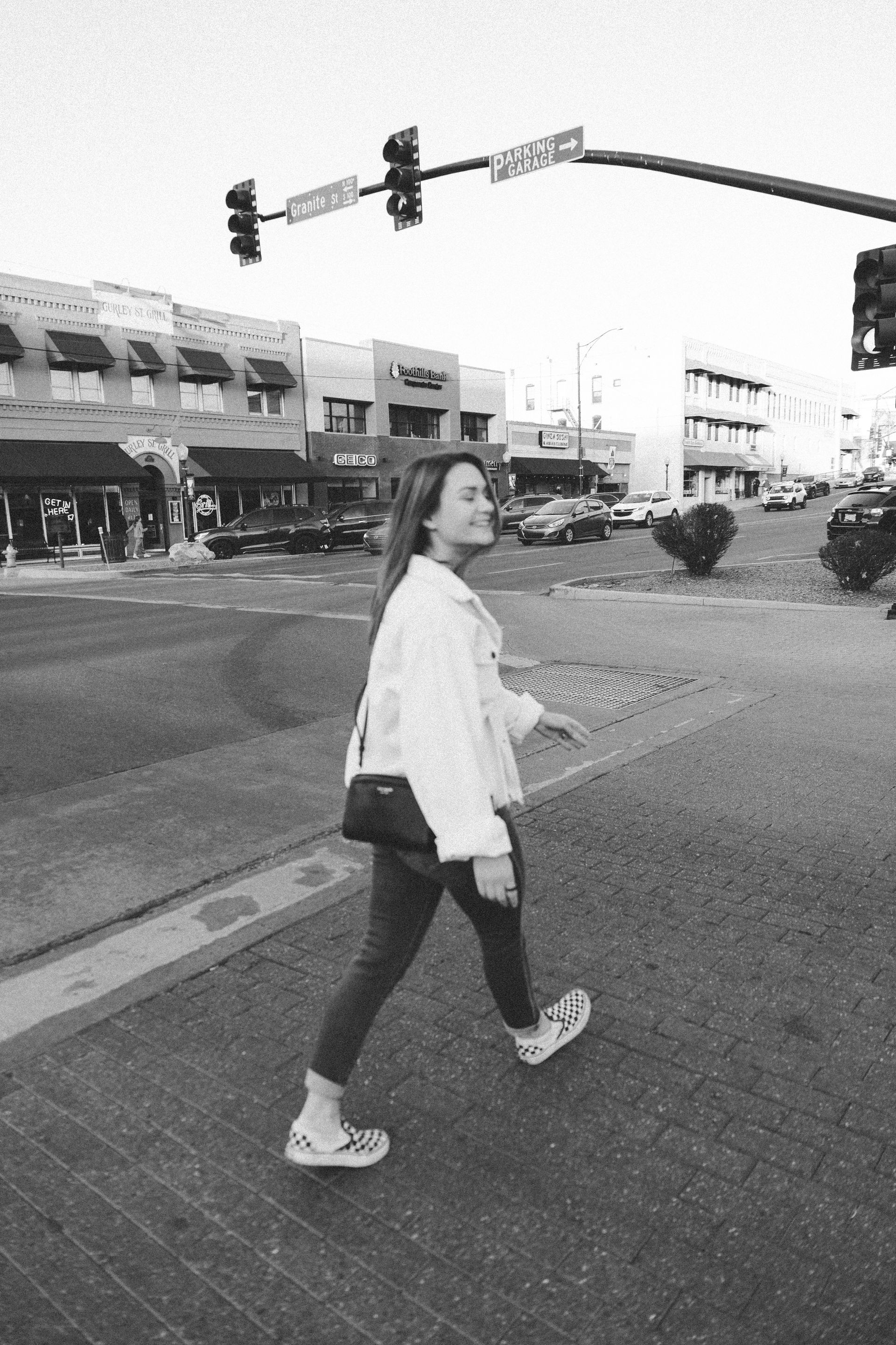 Bree is walking across a street in a black and white photo.