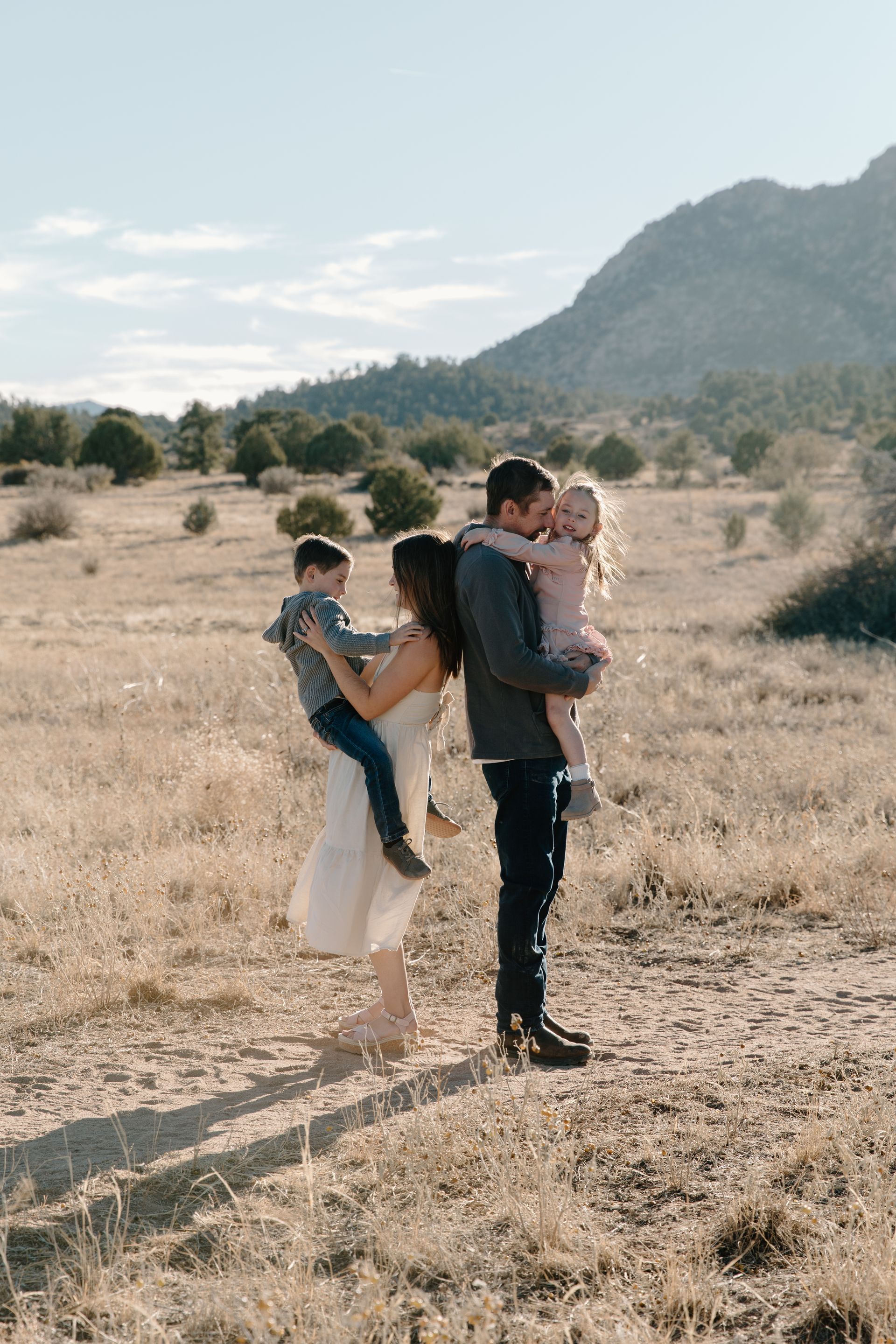 Bree's family is posing for a picture in a field with mountains in the background.