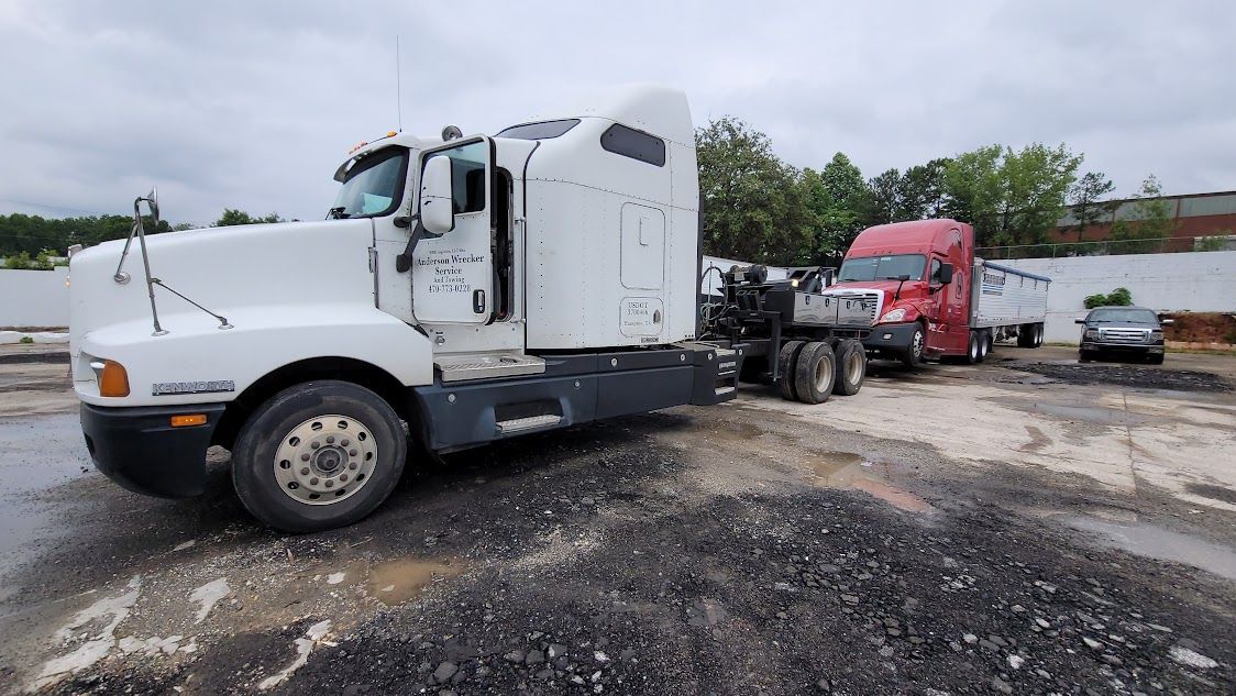 A white semi truck is parked next to a red semi truck in a parking lot.