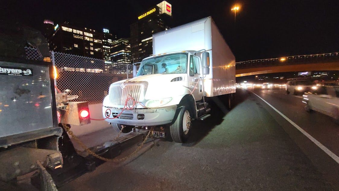 A white truck is sitting on the side of a highway at night. A white truck is sitting on the side of a highway at night.