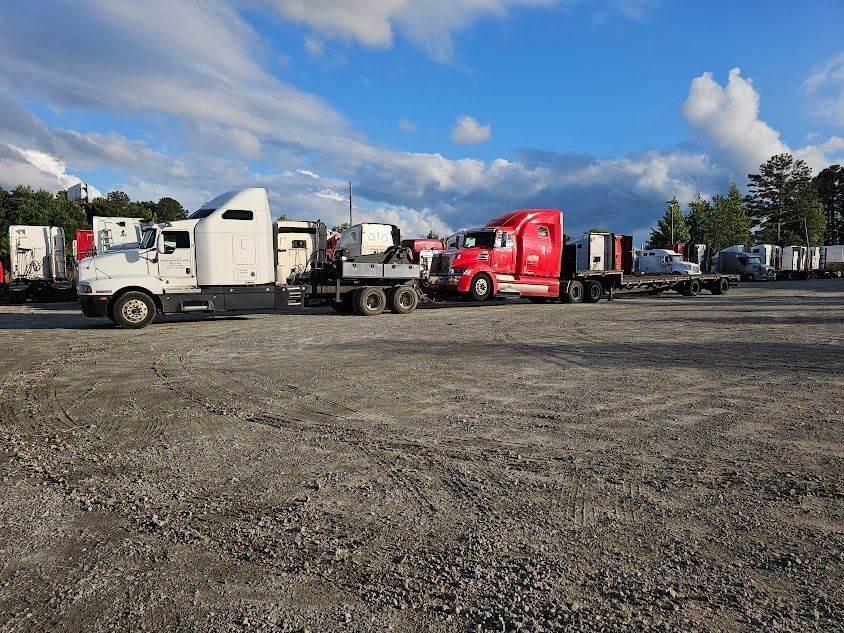 A white and red semi trucks are parked in a gravel lot.