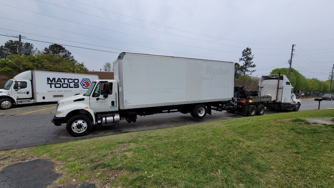 A couple of moving trucks are parked on the side of the road.