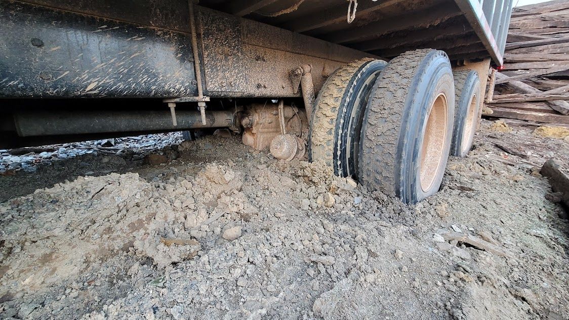 The tires of a dump truck are stuck in the mud.