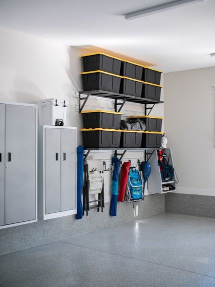 Garage storage system with shelves, bins, and hooks holding items; gray cabinets nearby.