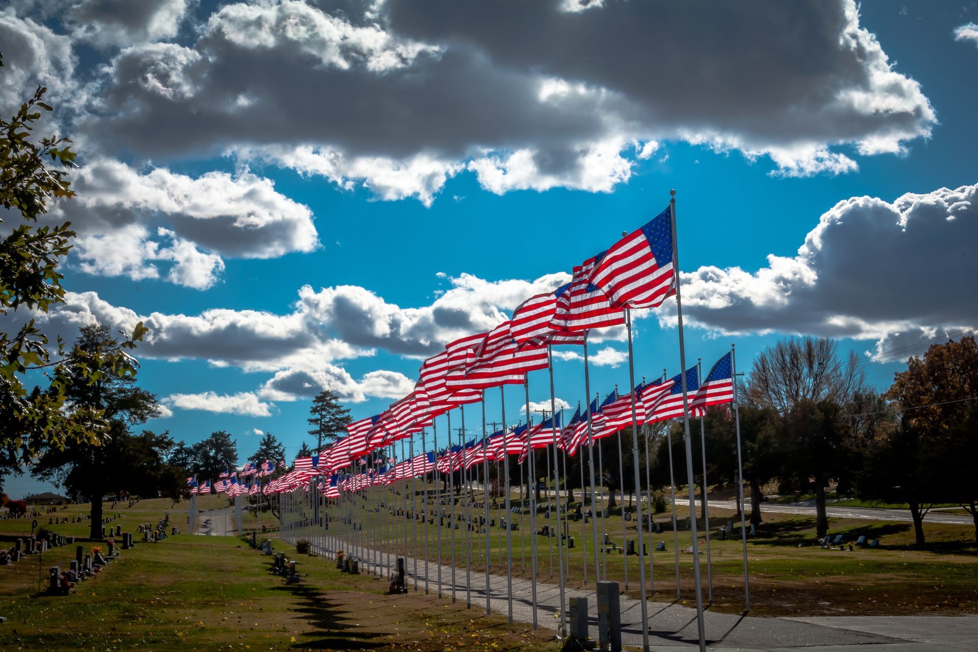 A woman is holding an american flag and a rose at a funeral.