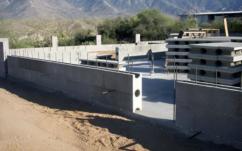 A concrete wall is being built with mountains in the background