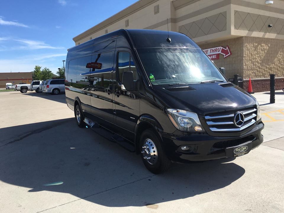 Black Mercedes-Benz Sprinter van parked at a gas station on a sunny day.