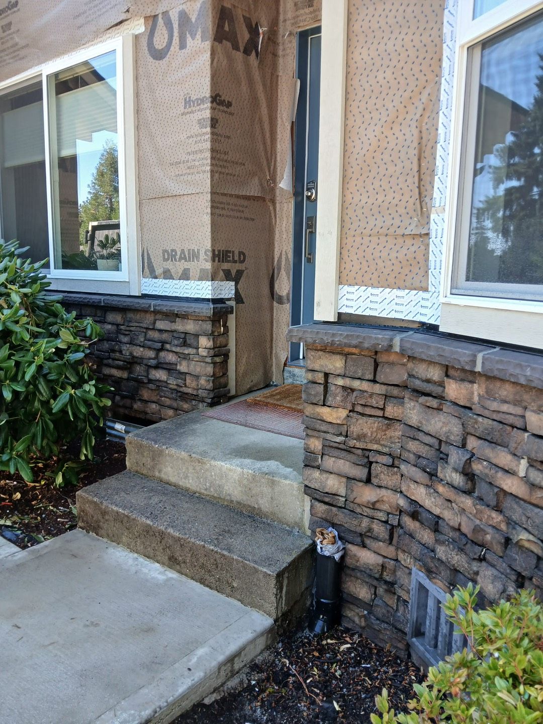 Stone steps and walkway leading to a house with a concrete porch and flower bed. Stone steps and walkway leading to a house with a concrete porch and flower bed.