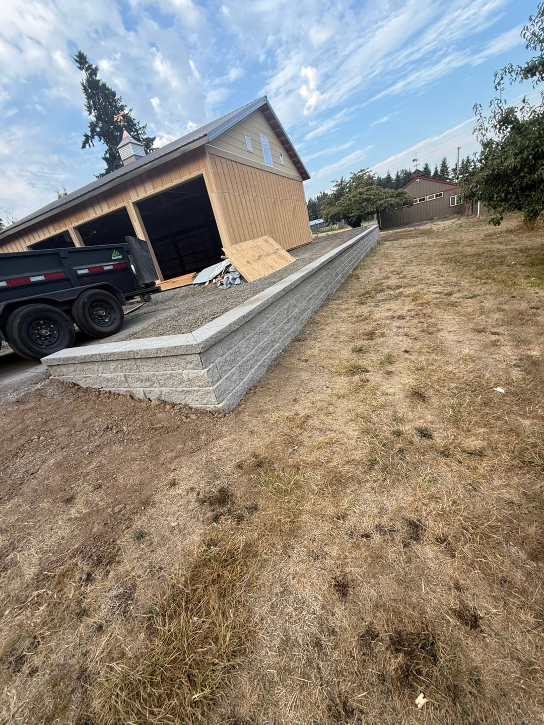 Stone retaining wall with steps, featuring greenery and grass.