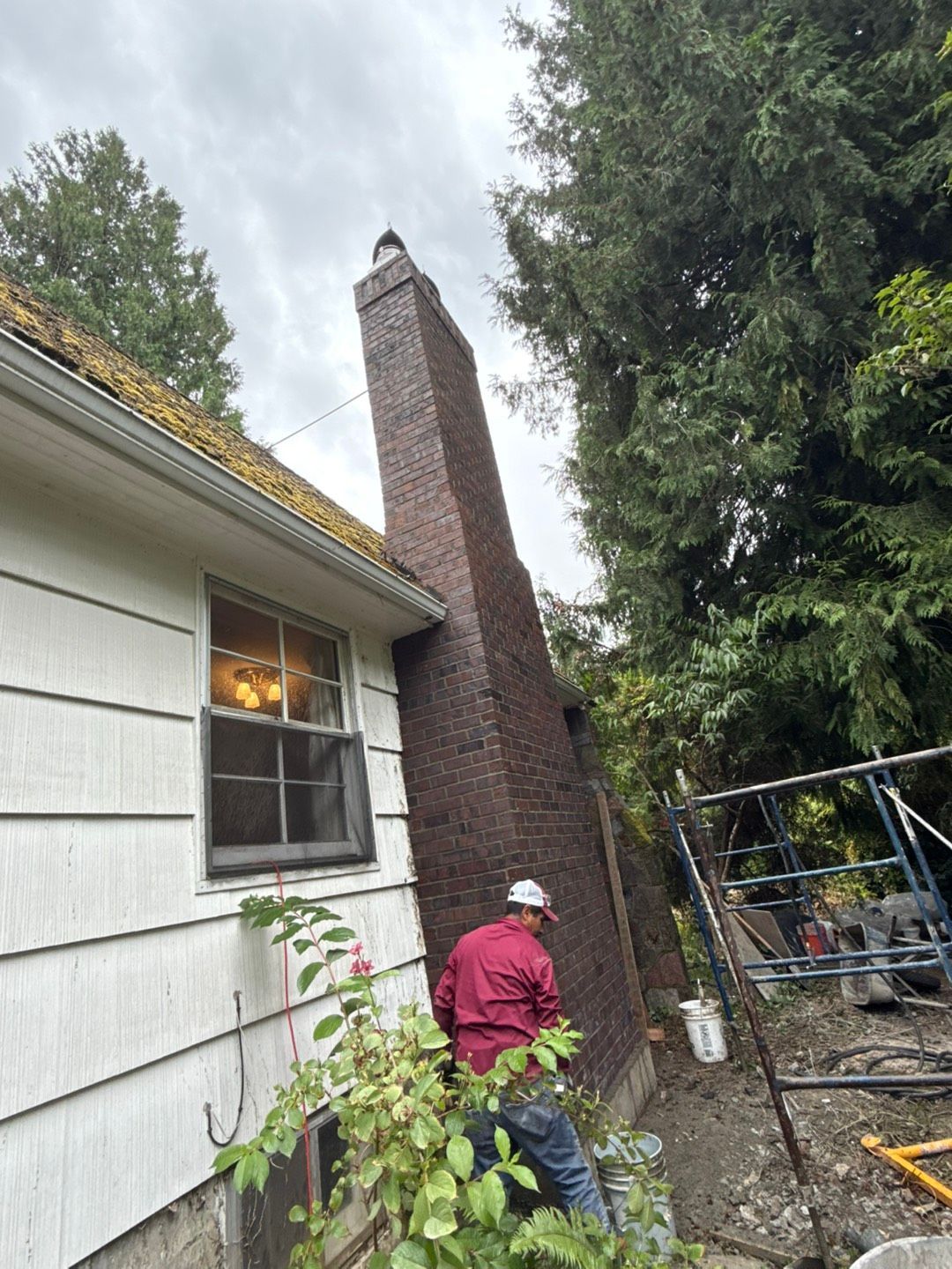 Brick chimney on a dark gray tiled roof against a blue sky. Brick chimney on a dark gray tiled roof against a blue sky.