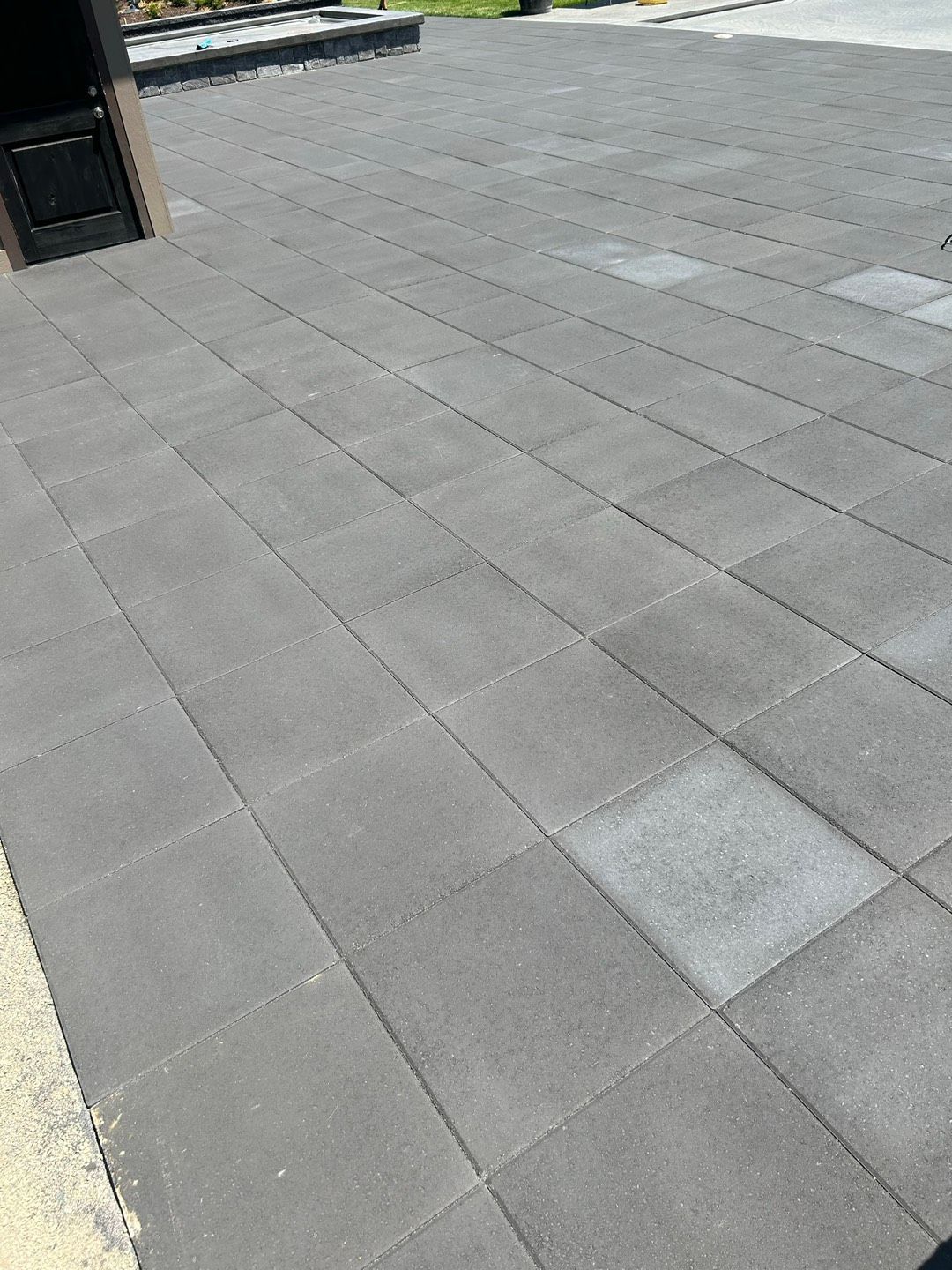 Backyard with square pavers, gravel, and a variety of plants, including a Japanese maple and evergreen shrubs.