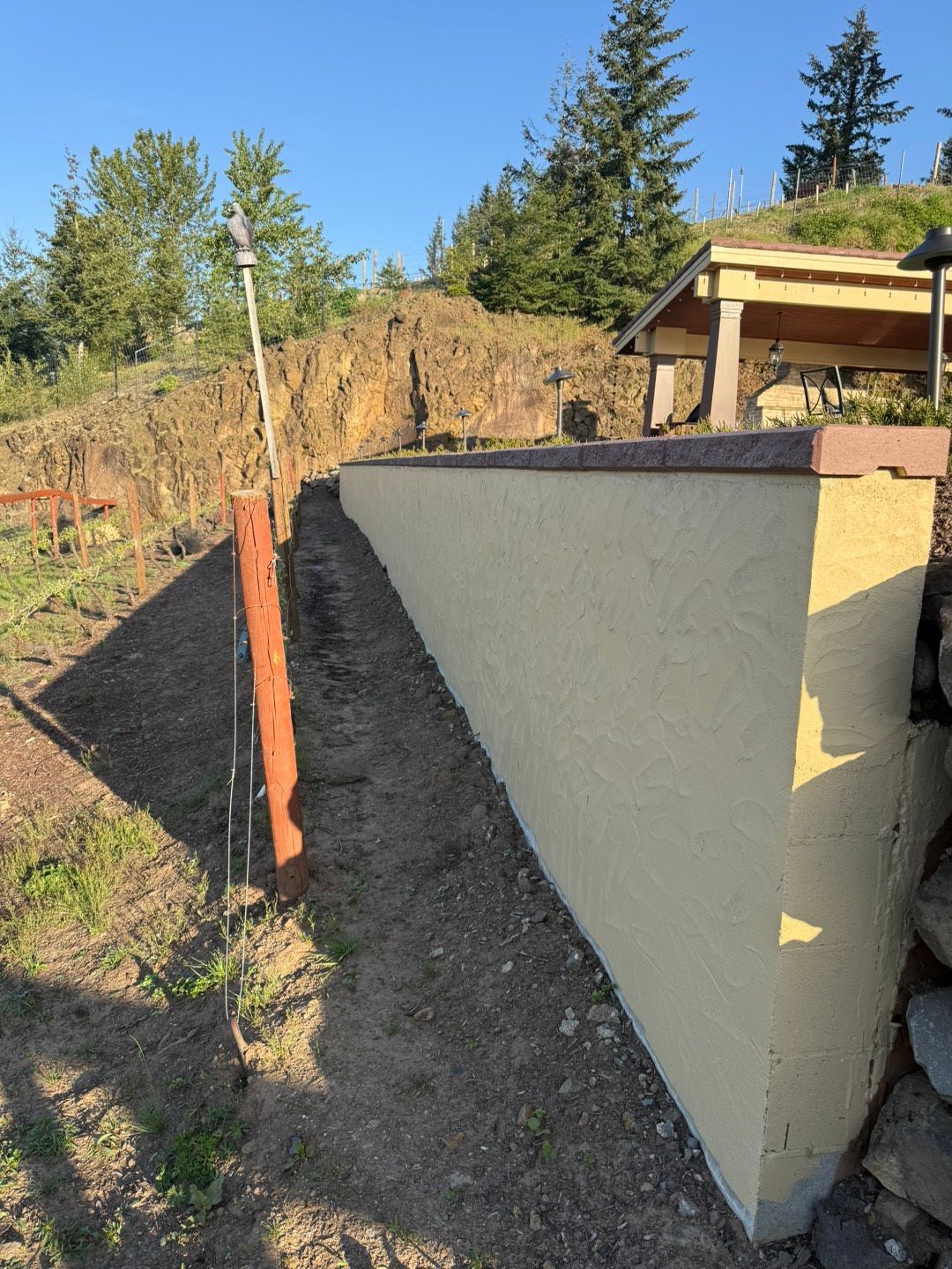 Person in blue sleeves and gloves using a trowel to apply mortar between stones in an outdoor setting. Person in blue sleeves and gloves using a trowel to apply mortar between stones in an outdoor setting.
