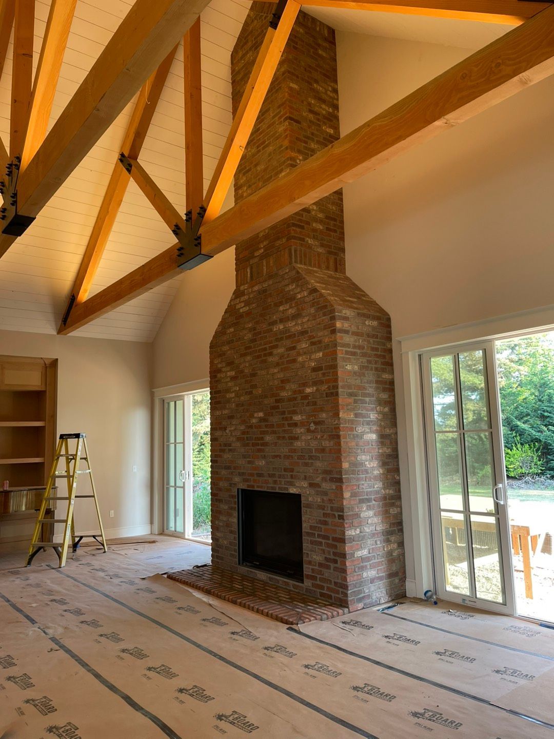 Fireplace with burning fire, stone surround, wooden mantel with books, copper bucket. Fireplace with burning fire, stone surround, wood mantle, copper log holder, books above.