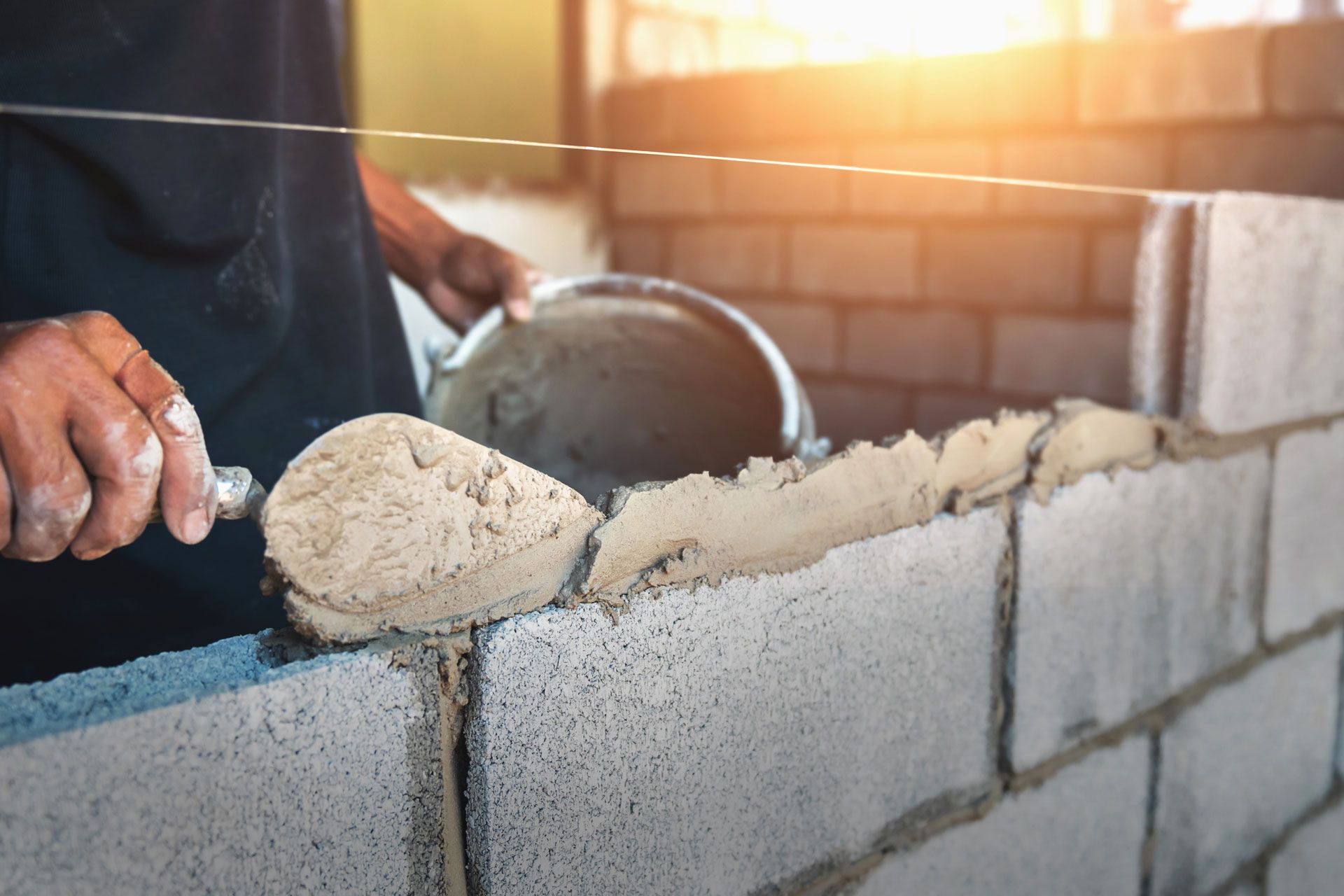 Bricklayer spreading mortar on cinder blocks.