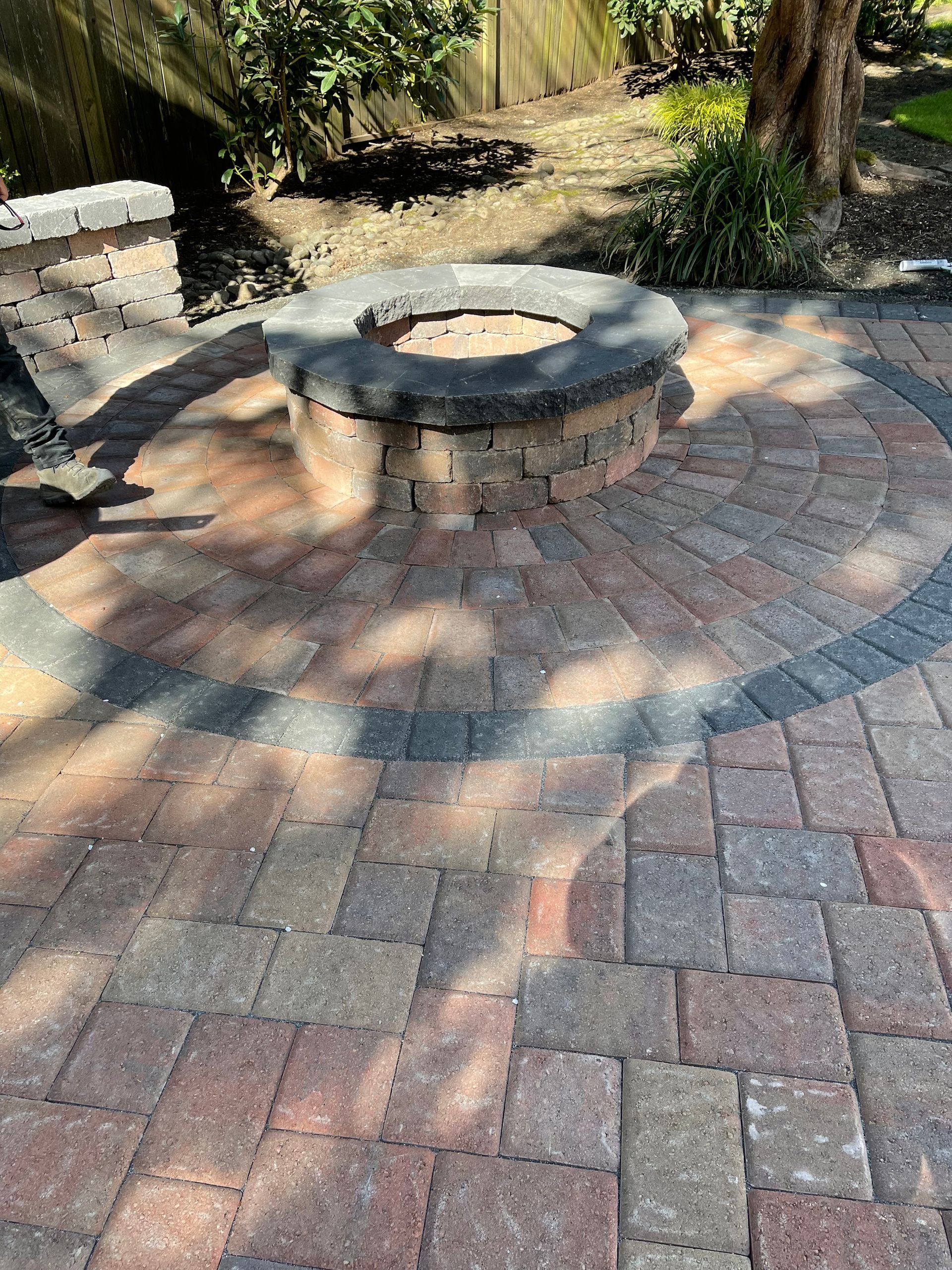 Person using a mallet to level paving stones on a sandy surface. Person using a mallet to level paving stones on a sandy surface.