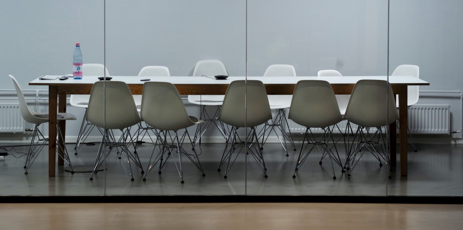 A conference room with a white table and chairs behind a glass wall.