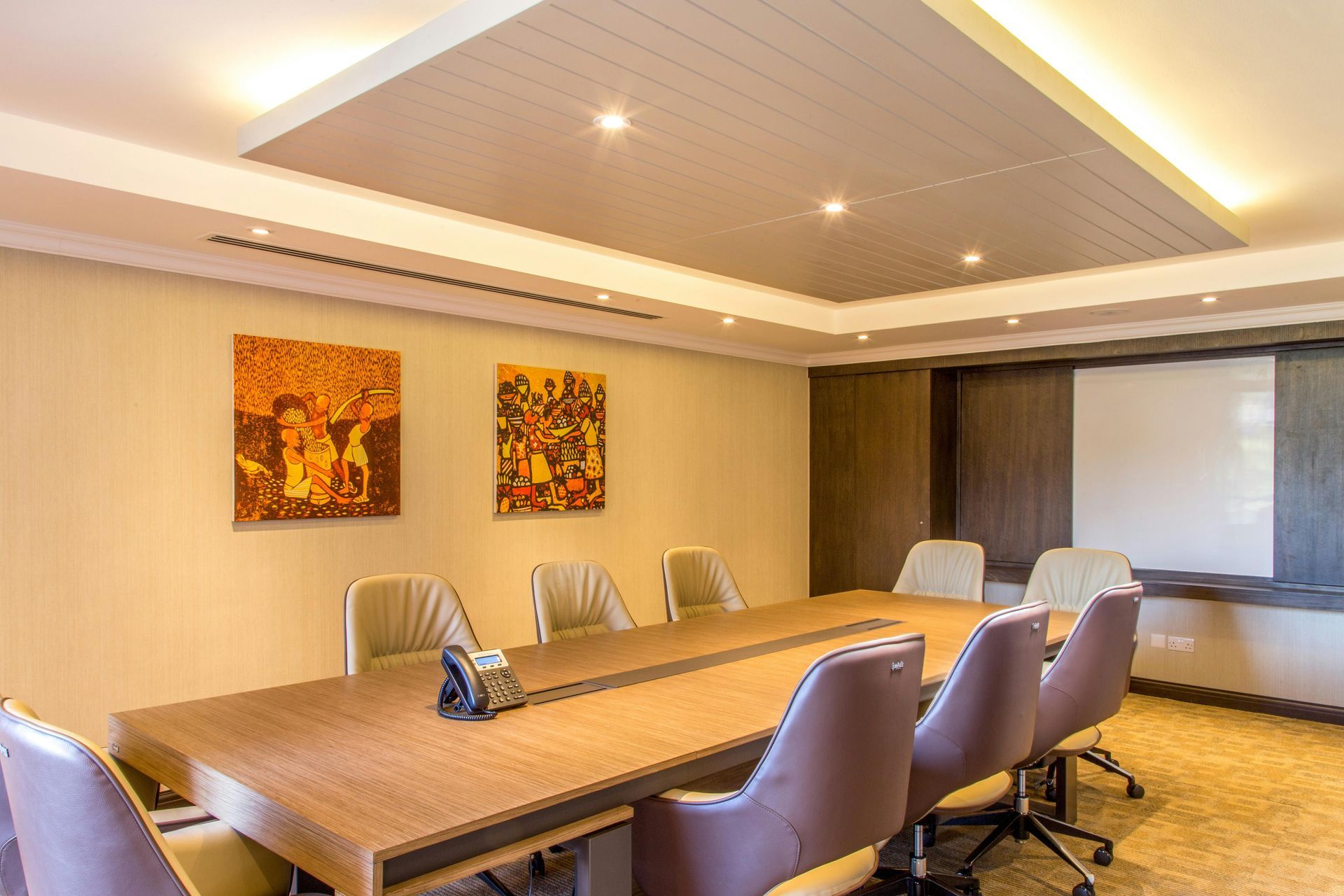 Modern conference room with long table, leather chairs, wall art, and recessed lighting