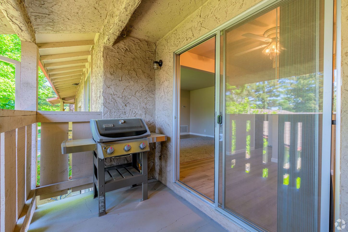 A grill is sitting on a balcony next to a sliding glass door.