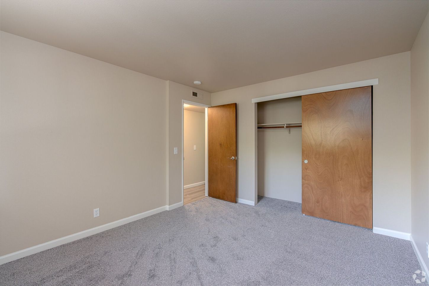An empty bedroom with a large closet and sliding doors.