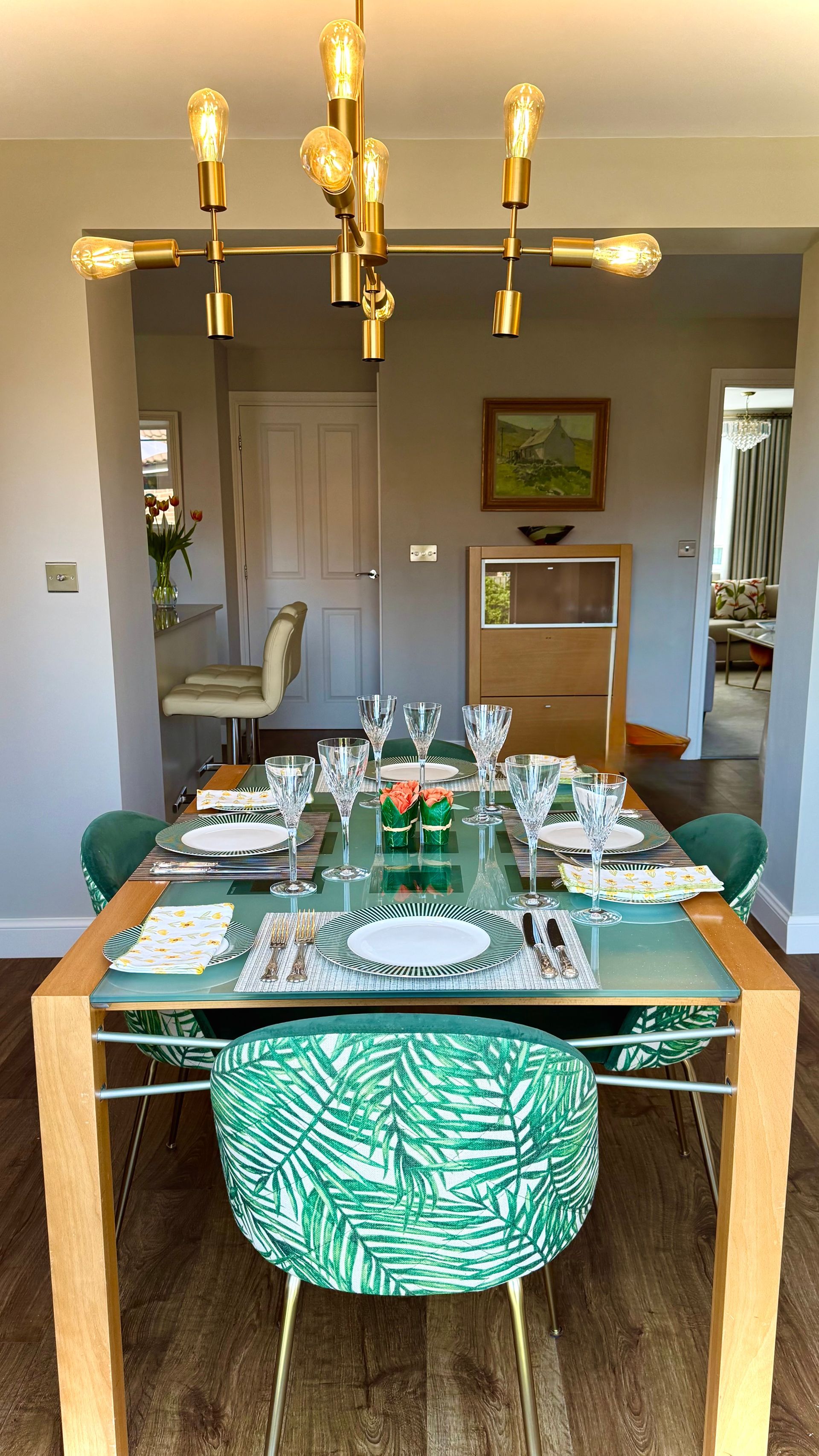 A dining room table with green chairs and a chandelier.