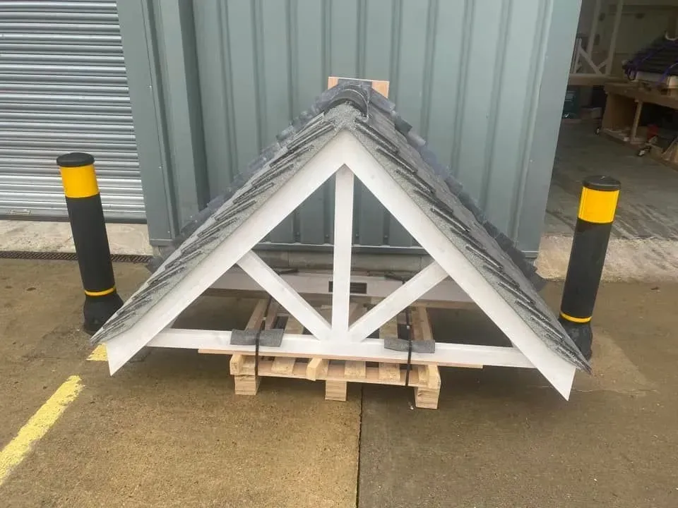 A triangle shaped structure is sitting on a wooden pallet in front of a building.