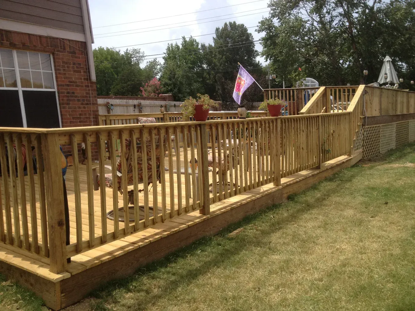A wooden deck with a brick house in the background