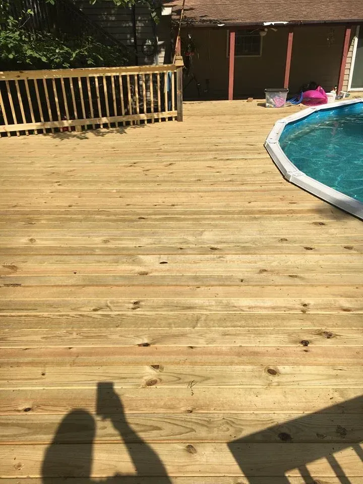 A wooden deck with a swimming pool in the background.