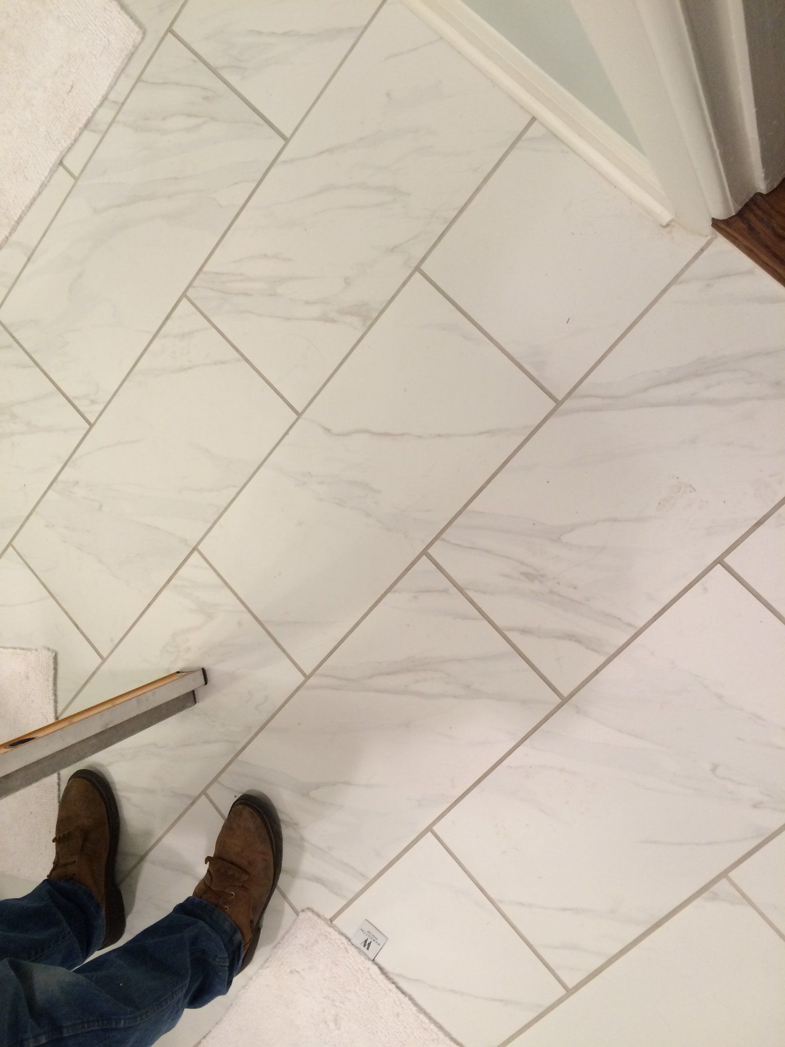 A person is standing on a white tile floor.