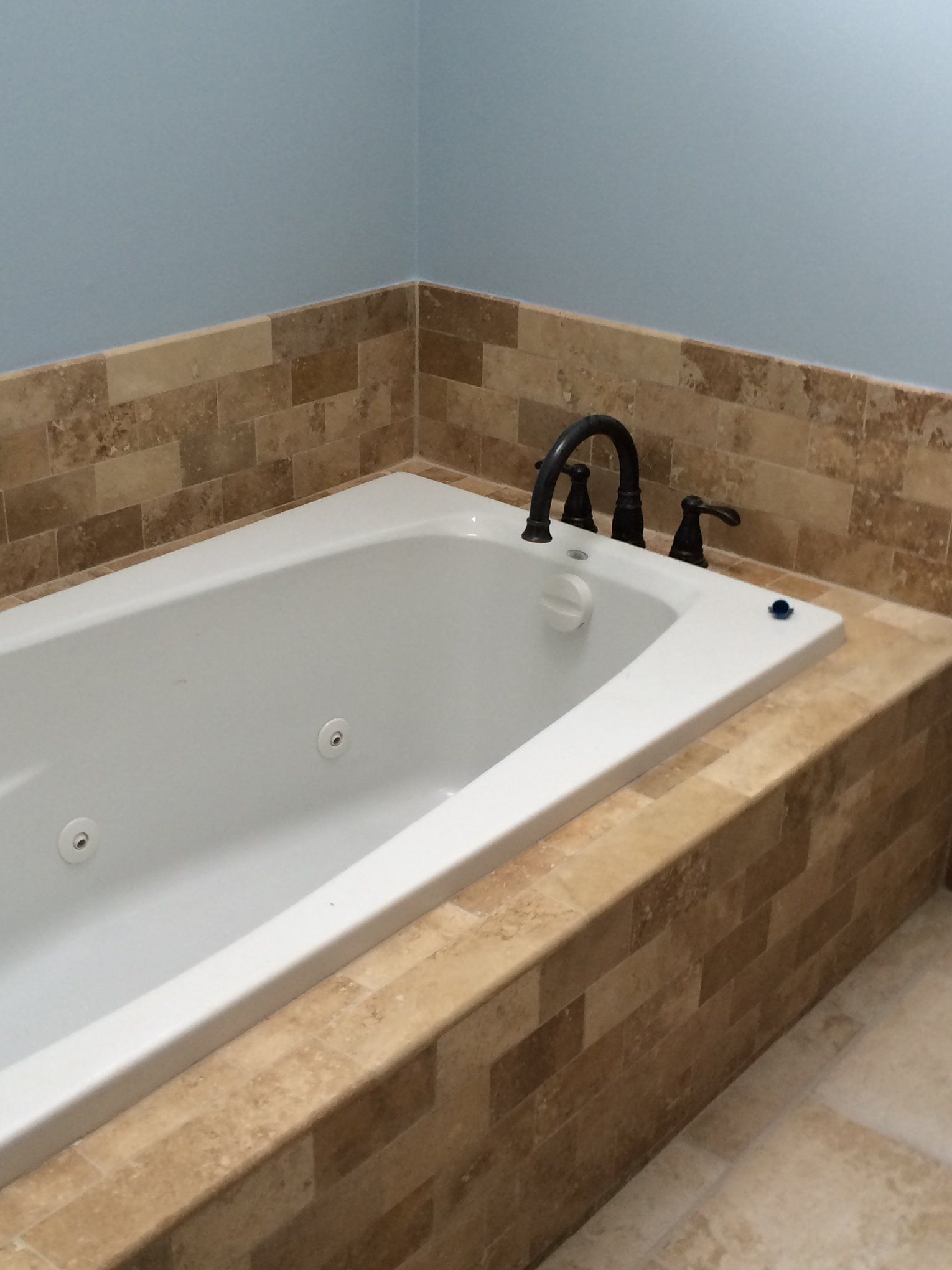 A bathtub in a bathroom with a tiled wall