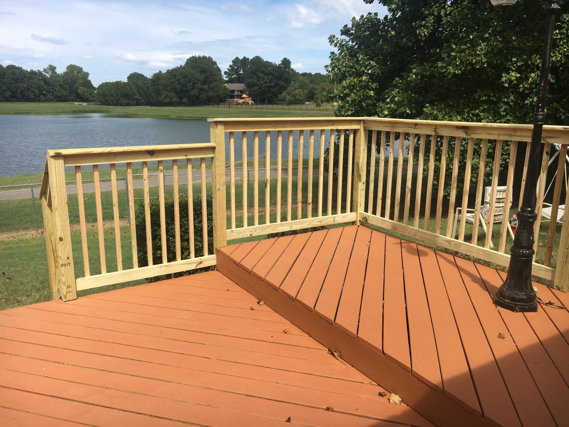 A wooden deck with a railing overlooking a lake