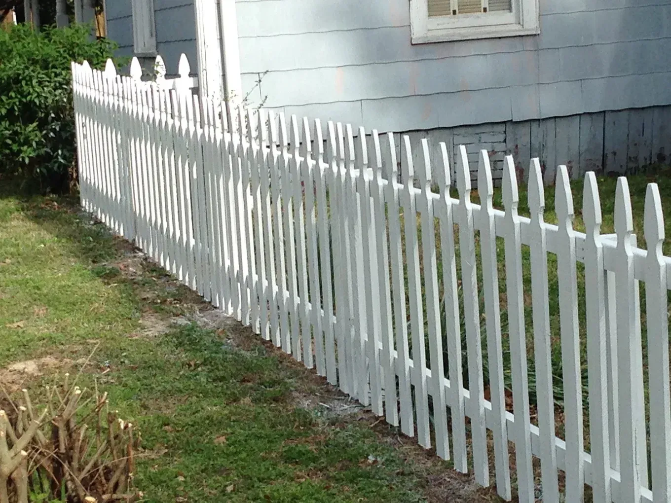 A white picket fence is in front of a house.