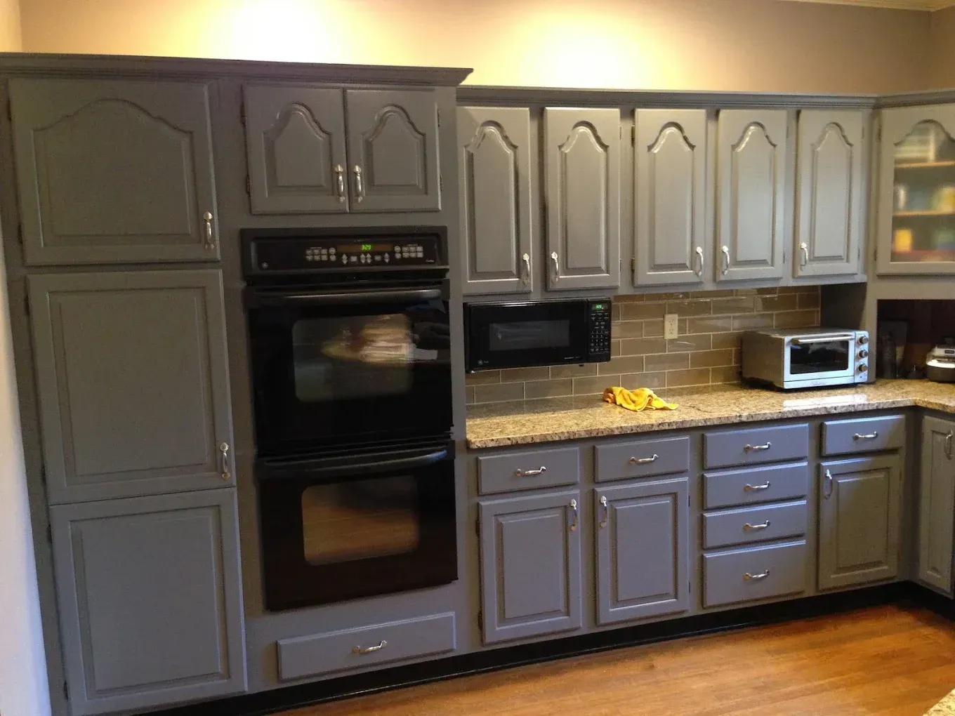 A kitchen with gray cabinets and black appliances