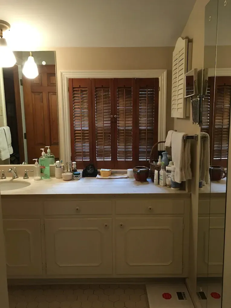 A bathroom with a sink , mirror and window.