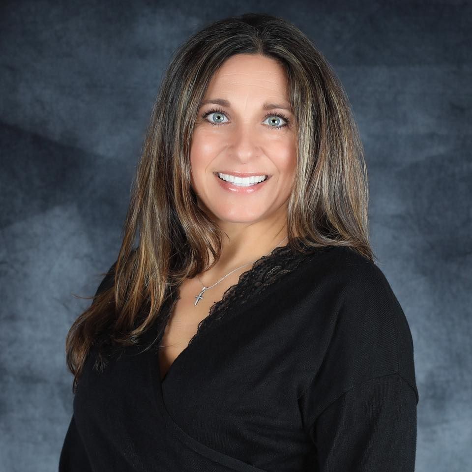Terri Pouti of AMR Insurance Group wearing a black shirt and a necklace is smiling for the camera.